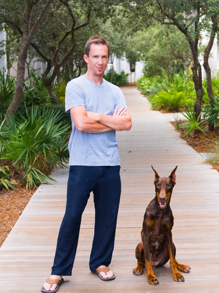 Aaron McDonald, arms folded, beside his Doberman